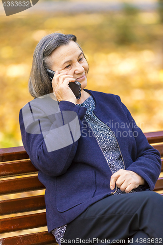 Image of Senior woman talking on smartphone outdoors