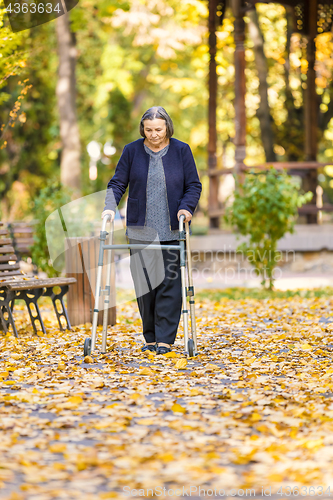 Image of Senior woman with walker walking outdoors