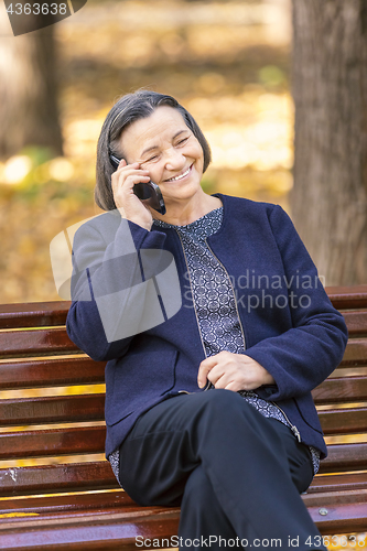 Image of Senior woman talking on smartphone outdoors