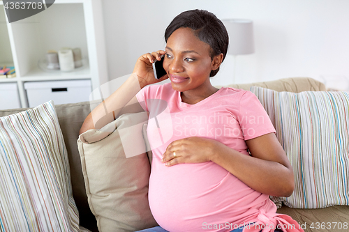 Image of happy pregnant woman calling on smartphone at home