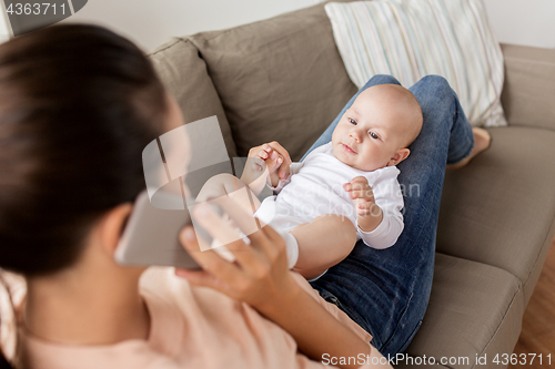 Image of mother with baby calling on smartphone at home