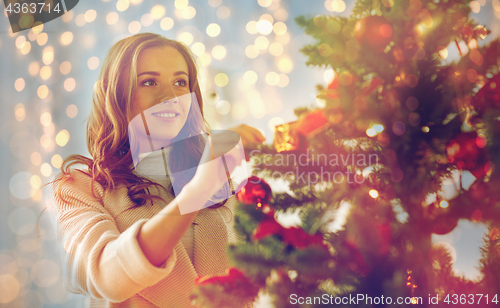 Image of happy young woman decorating christmas tree