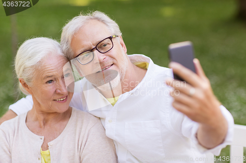 Image of senior couple taking selfie by smartphone at park