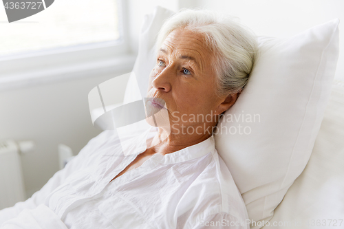 Image of sad senior woman lying on bed at hospital ward