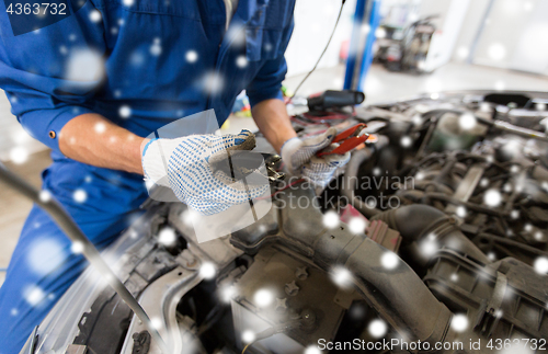 Image of auto mechanic hands with cleats charging battery