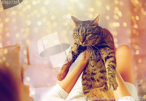 Image of young woman with cat lying in bed at home