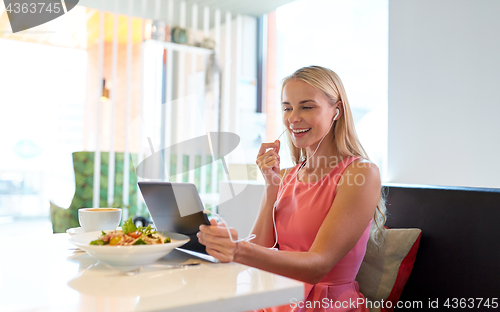 Image of happy young woman with tablet pc at restaurant