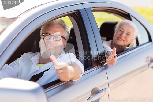 Image of senior couple driving in car and showing thumbs up