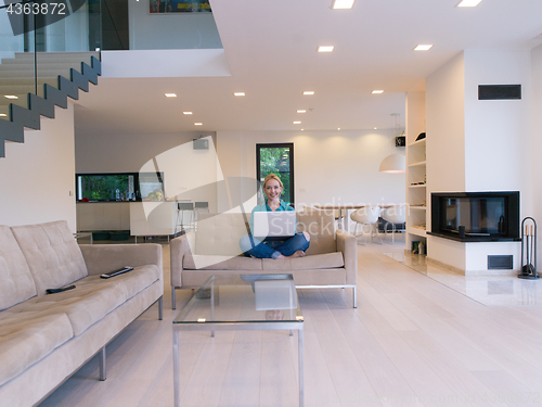 Image of Young woman using laptop at home