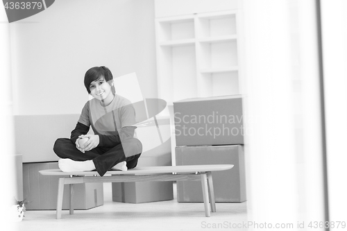 Image of boy sitting on the table with cardboard boxes around him