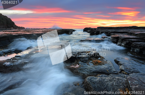 Image of Sunrise waves flowing into rock chasm seascape