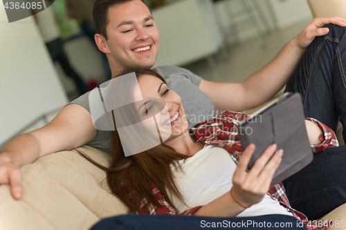 Image of couple relaxing at  home with tablet computers