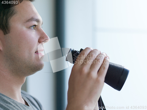 Image of man looking with binoculars