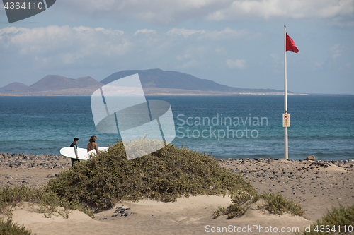 Image of The red flag weighs in the wind at Surfers Beach Famara on Lanza