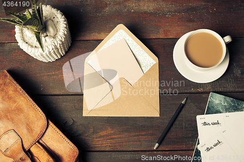 Image of Opened craft paper envelope , autumn leaves and coffee on wooden table