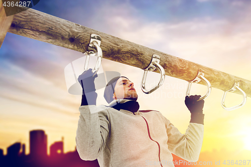 Image of young man exercising on horizontal bar in winter