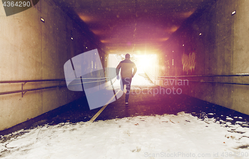 Image of man running along subway tunnel in winter