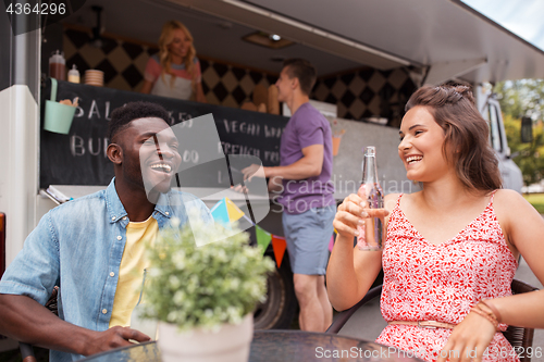 Image of friends with drinks sitting at table at food truck