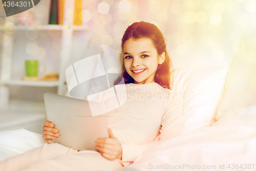 Image of happy girl lying in bed with tablet pc at home