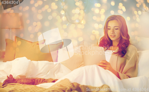 Image of happy young woman with tablet pc in bed at home
