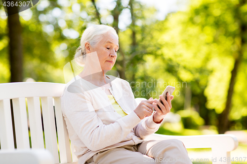 Image of senior woman with smartphone at summer park