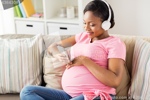 Image of pregnant woman in headphones with smartphone