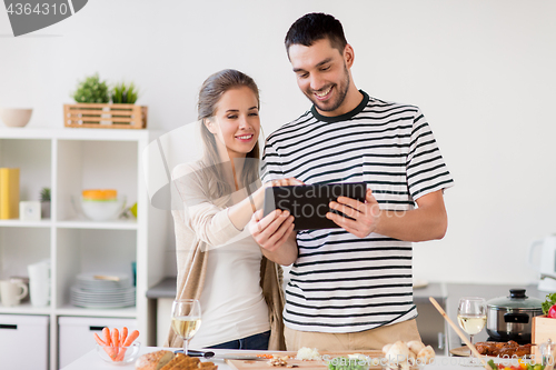 Image of happy couple with tablet pc cooking food at home