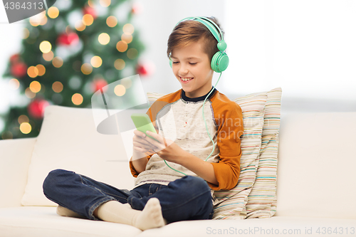 Image of boy with smartphone and headphones at christmas