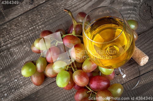 Image of Glass of white wine with a cluster of grapes