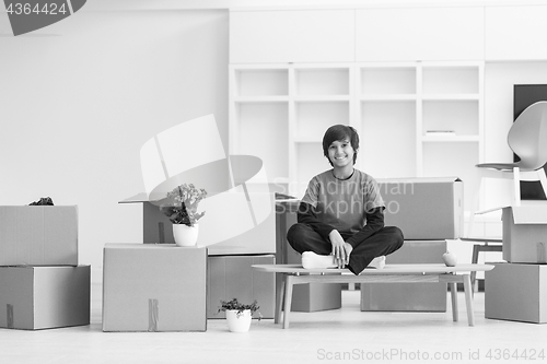 Image of boy sitting on the table with cardboard boxes around him