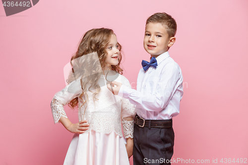 Image of Boy and girl standing in studio on pink background