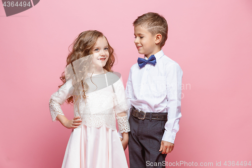 Image of Boy and girl standing in studio on pink background