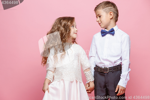 Image of Boy and girl standing in studio on pink background
