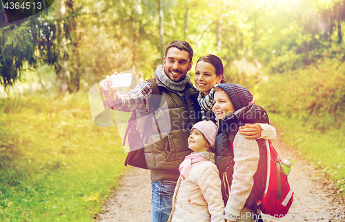 Image of family with backpacks taking selfie by smartphone