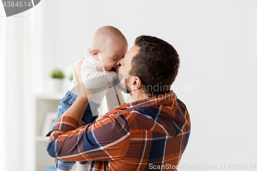 Image of happy father kissing little baby boy at home