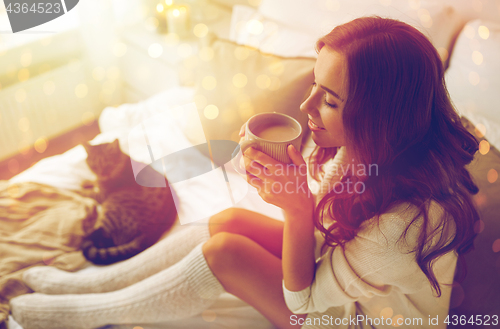 Image of happy woman with cup of coffee in bed at home