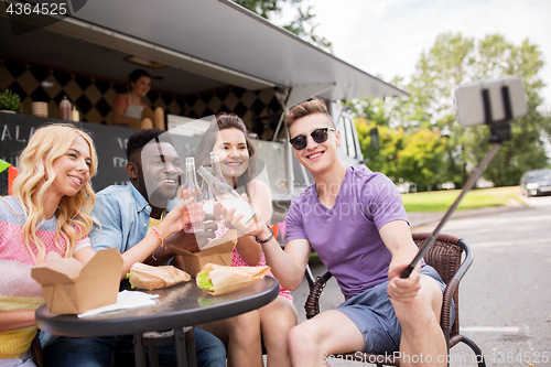 Image of happy young friends taking selfie at food truck