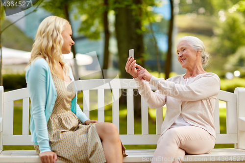 Image of senior mother photographing daughter by smartphone