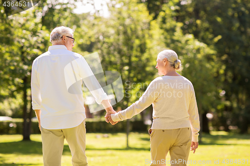 Image of happy senior couple walking at summer park