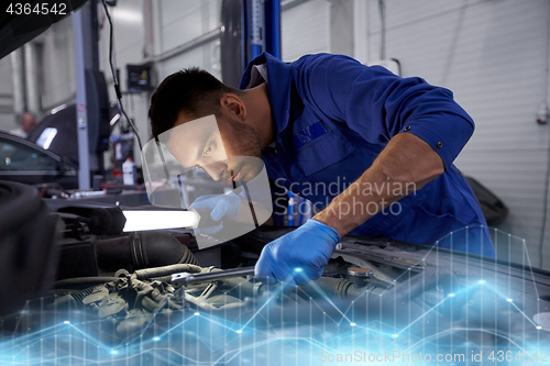 Image of mechanic man with lamp repairing car at workshop