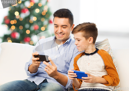 Image of happy father and son with smartphones at christmas