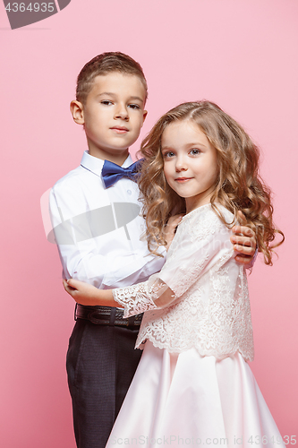 Image of Boy and girl standing in studio on pink background
