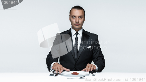 Image of Bloody Halloween theme: crazy man with a knife, fork and meat