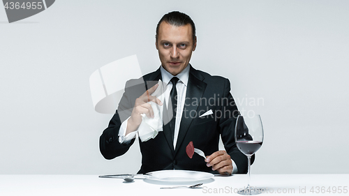 Image of Bloody Halloween theme: crazy man with a knife, fork and meat