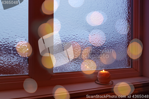 Image of Cozy frosted window, candle and bokeh lights