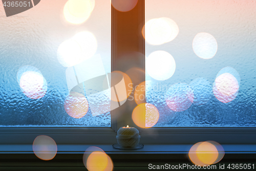 Image of Frosted window, bokeh lights, and burning candle