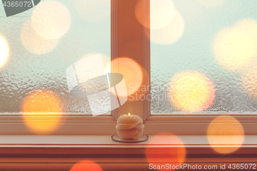 Image of Cozy candle on a windowsill in golden light