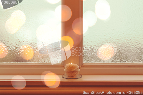 Image of Frosted winter window and candle in golden light