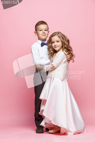 Image of Boy and girl standing in studio on pink background