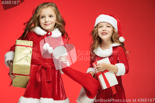 Image of Two happy girls in santa claus hats with gift boxes